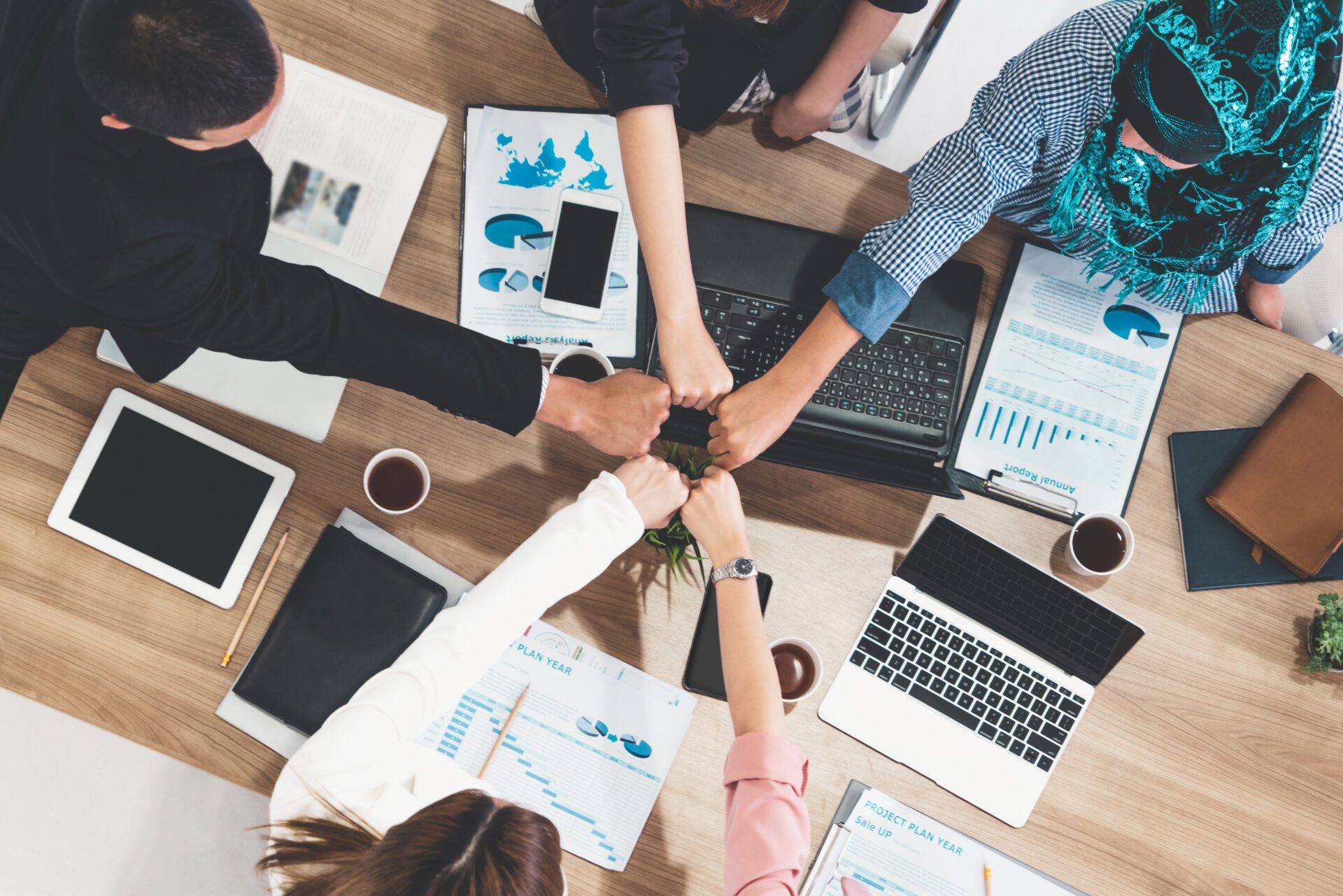 Businessmen and businesswomen joining hands in group meeting at multicultural office room showing teamwork, support and unity in business. Diversity workplace and corporate people working concept.